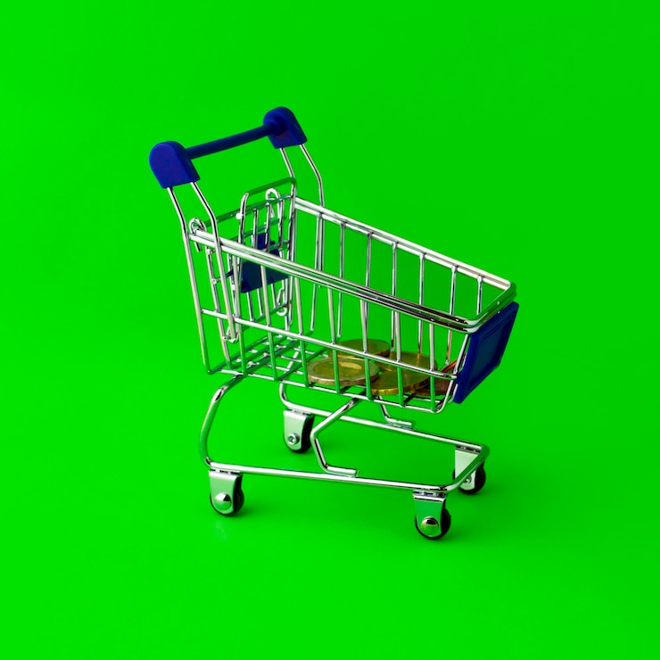 Foto carro de compras con monedas de euro en un fondo verde
