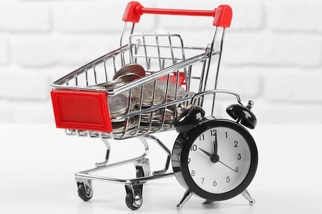 Carro de compras con monedas y reloj