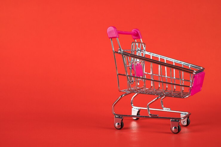 Foto carro de compras o carrito de supermercado sobre fondo rojo.
