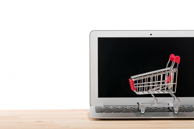 Carro de compras rojo en una computadora portátil aislada en blanco.