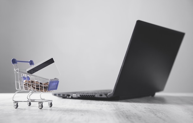 Carro de compras con tarjeta de crédito y laptop.