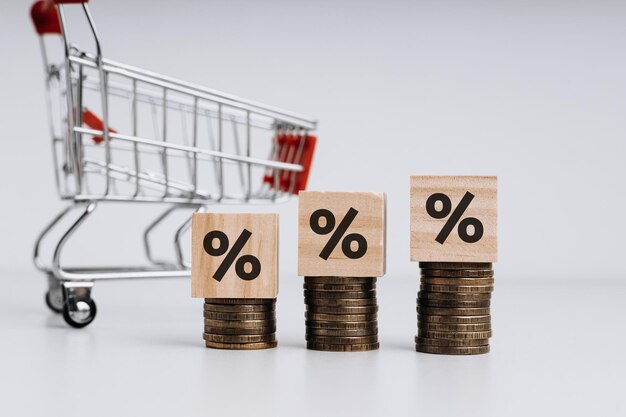 Carro de compras vacío con cubos de madera con porcentaje y pila de monedas