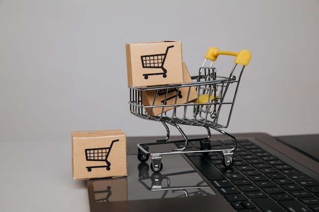 Carro de concepto de ventas en línea con cajas de papel en un primer plano del teclado
