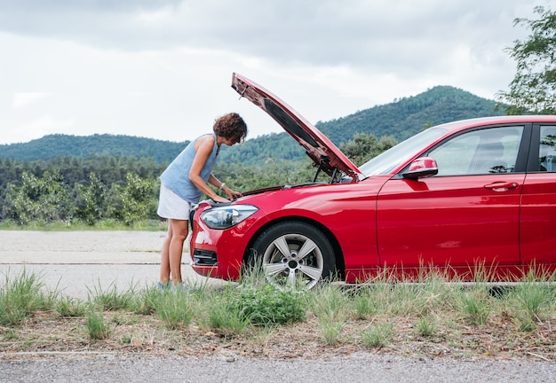 carro danificado, mulher olha para o motor