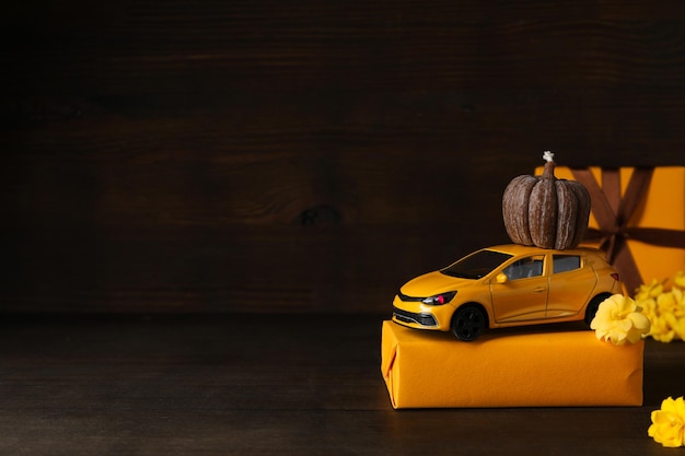 carro de brinquedo amarelo com uma abóbora presente e flores lugar para texto