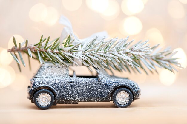 Carro de brinquedo coberto de neve com uma árvore de Natal em um fundo de bokeh Conceito de Natal