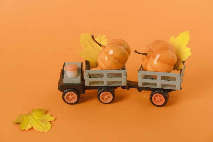 Foto carro de brinquedo com abóboras e folhas de outono em fundo laranja conceito de colheita de halloween e outono