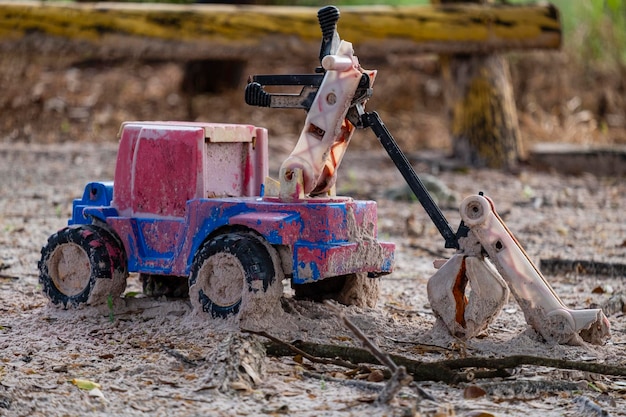 Carro de brinquedo de plástico danificado e abandonado na areia