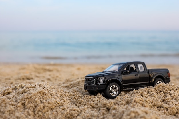 Carro de brinquedo na areia contra o fundo do mar