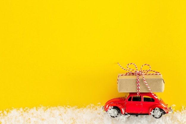 Carro de brinquedo vermelho carregando uma caixa de presente de Natal