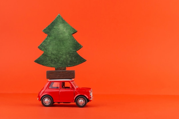 Carro de brinquedo vermelho com uma árvore de natal no telhado