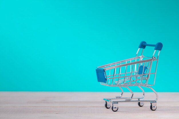 Carro de compras em emtye em mesa de madeira com fundo azul