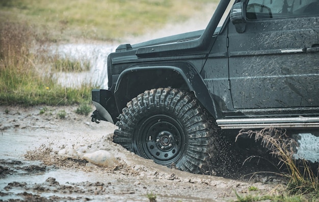 Carro de jipe offroad na lama da estrada de cascalho ruim e respingos de água em viagens offroad de corrida na montanha