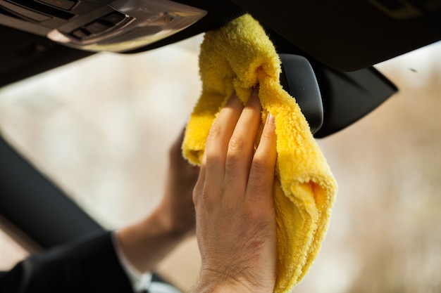 Foto carro de limpeza. mão com pano de microfibra limpeza interior do carro