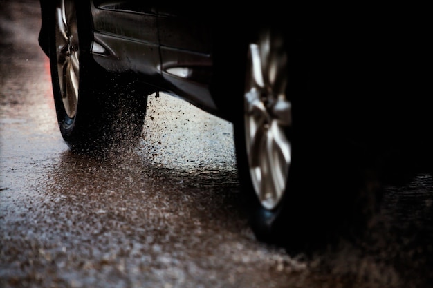 Carro de movimento na grande poça de chuva com água salpicando das rodas