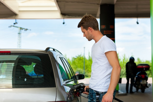 Foto carro de reabastecimento do homem no posto de gasolina