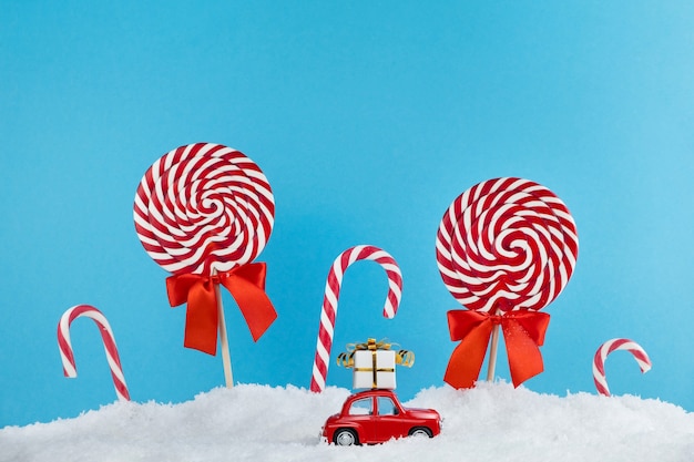 Carro do Papai Noel vermelho com presente no telhado em uma floresta de árvores de Natal com doces e bombons de pirulitos