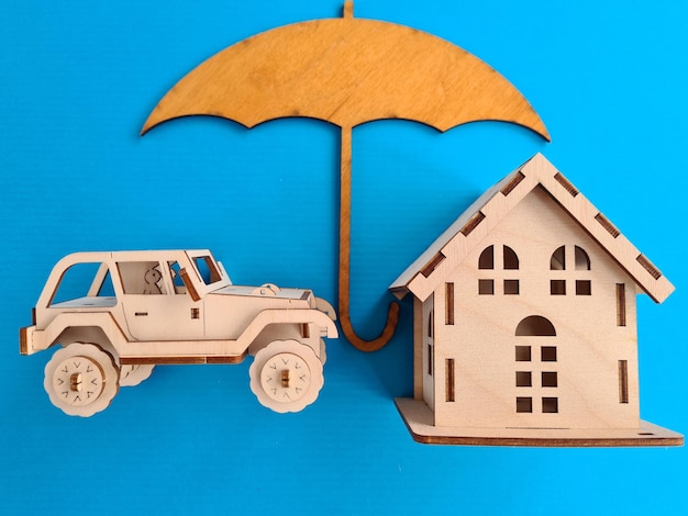 Carro e casa de madeira sob um guarda-chuva e seguro