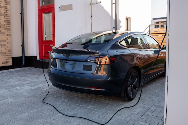 Carro elétrico preto sendo carregado na estação