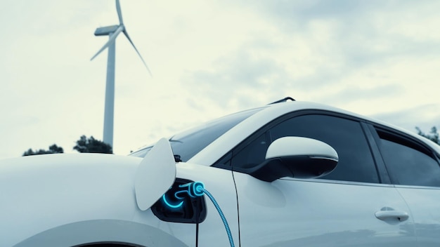 Carro elétrico recarregando energia da estação de carregamento por carregador inteligente de EV em fazenda de turbinas eólicas com natureza ao ar livre Avanço tecnológico de energia sustentável limpa alternativa Peruse