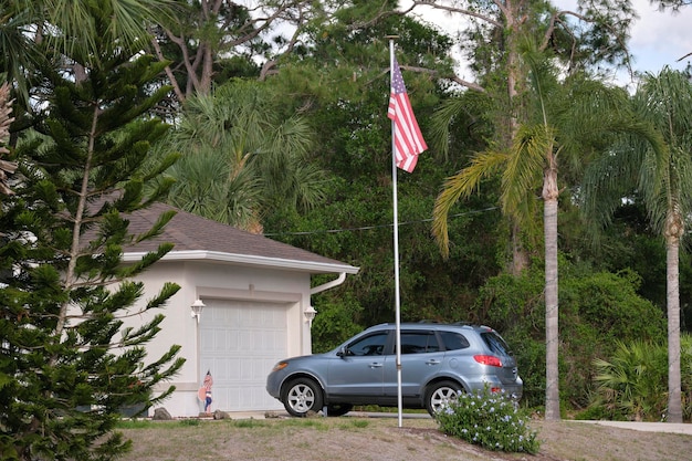 Carro estacionado em frente à ampla porta dupla da garagem na entrada de concreto da nova casa americana moderna