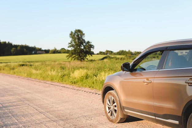 Carro estacionado na zona rural na paisagem rural e céu azul ao pôr do sol Conceito de viagem de transporte de verão