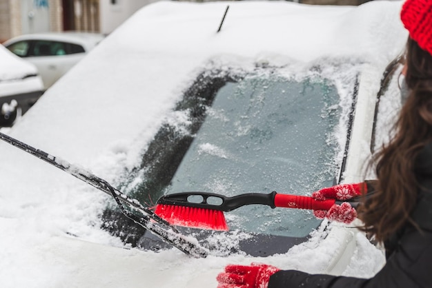 Carro limpo de mulher com escova depois da neve