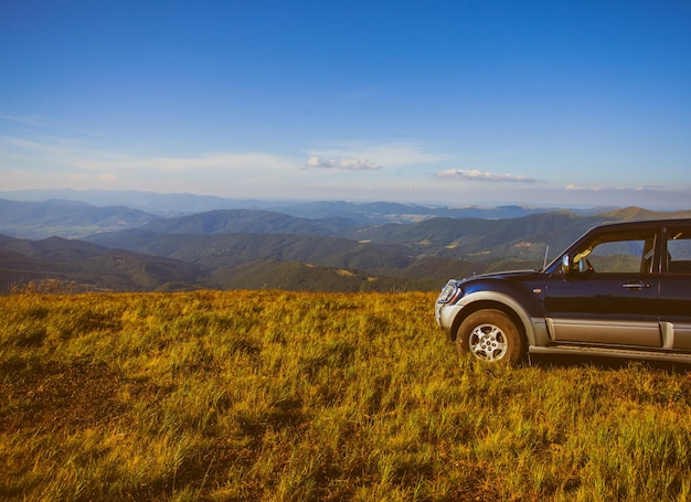 Carro na colina ao longo das montanhas, contra o céu azul. Viajar de SUV