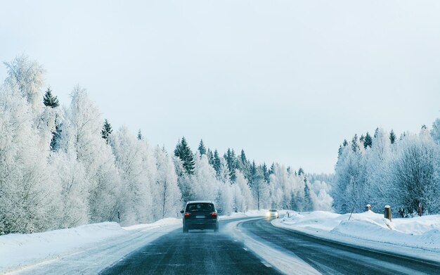 Carro na estrada de inverno com neve na Finlândia. Auto e paisagem fria da Lapônia. Automóvel na floresta da Europa. Passeio pela estrada da cidade finlandesa. Estrada e rota viagem de rua nevada. Dirigindo