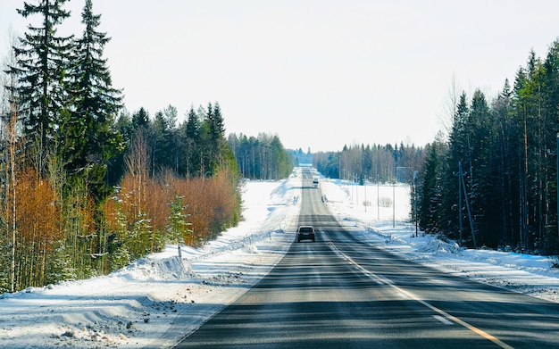 Carro na estrada de inverno com neve na finlândia. auto e paisagem fria da lapônia. automóvel na floresta da europa. passeio pela estrada da cidade finlandesa. estrada e rota viagem de rua nevada. dirigindo