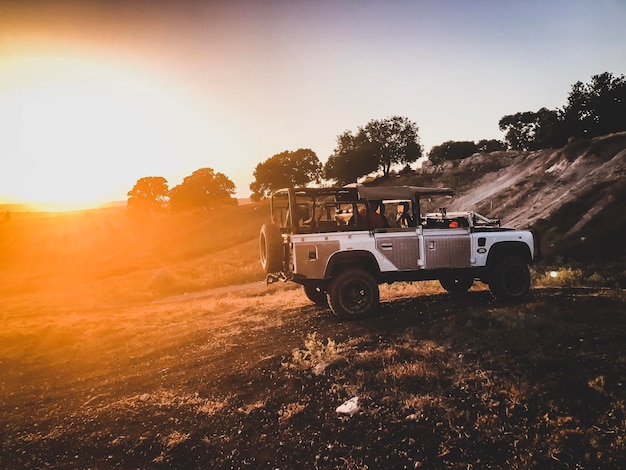 Foto carro no campo contra o céu claro durante o pôr do sol