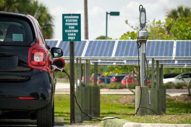 Carro plug-in elétrico carregando com eletricidade de fonte de energia renovável solar estacionada na rua da cidade