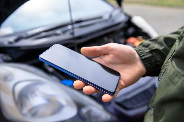 Carro quebrado e telefone de mão do homem