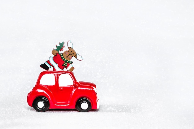 Carro retrô de brinquedo vermelho entregando cervos de Natal no telhado em fundo prateado de neve. Conceito de feliz Natal e feliz ano novo. Copie o espaço.