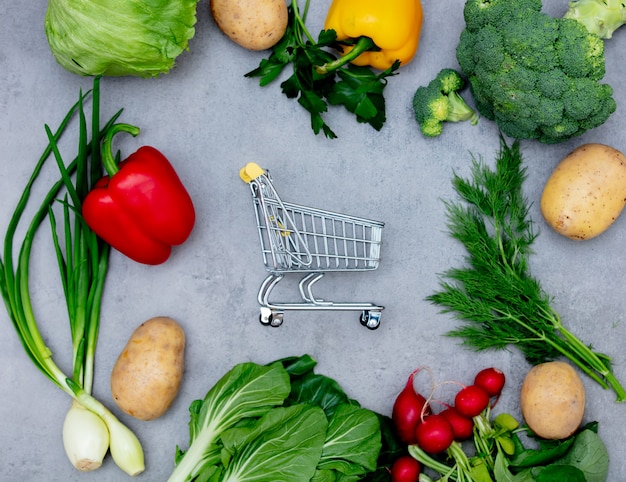 Carro de supermercado y verduras en una mesa