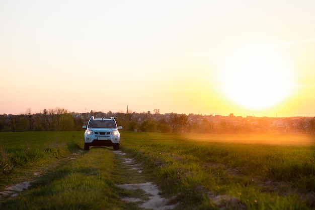 Carro suv branco na estrada de campo no pôr do sol
