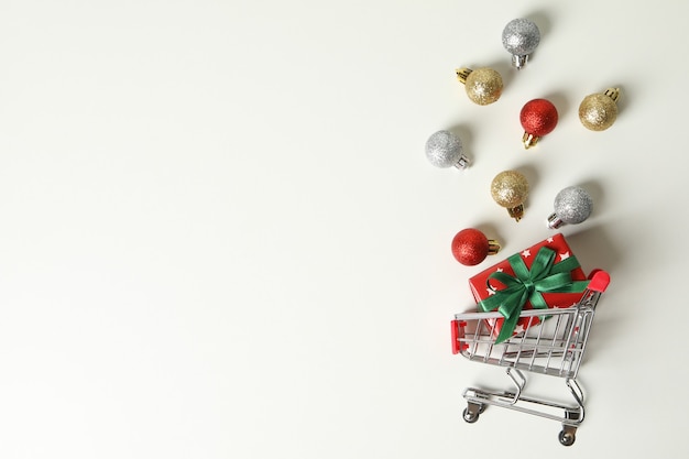 Carro de la tienda con caja de Navidad y adornos en blanco