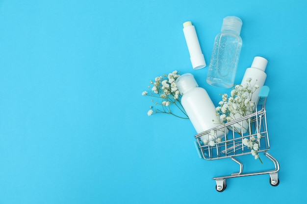 Carro de la tienda con cosméticos sobre fondo azul.