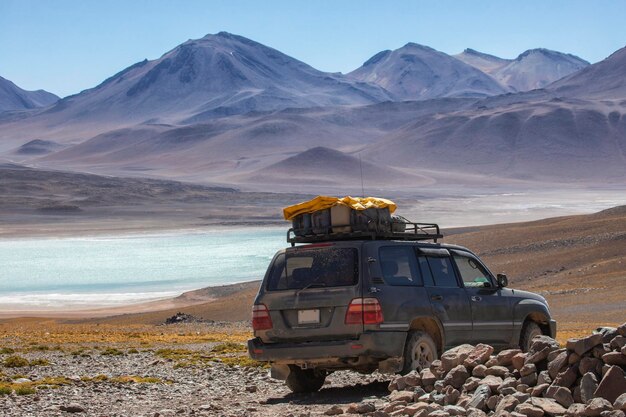 Carro turístico SUV perto do lago contra o pano de fundo das montanhas na Bolívia