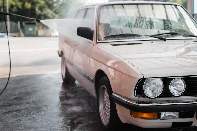 Foto carro velho sendo lavado com mangueira de água