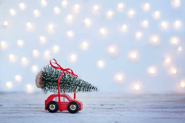 Carro vermelho em miniatura com árvore de Natal em fundo de madeira. Conceito de férias