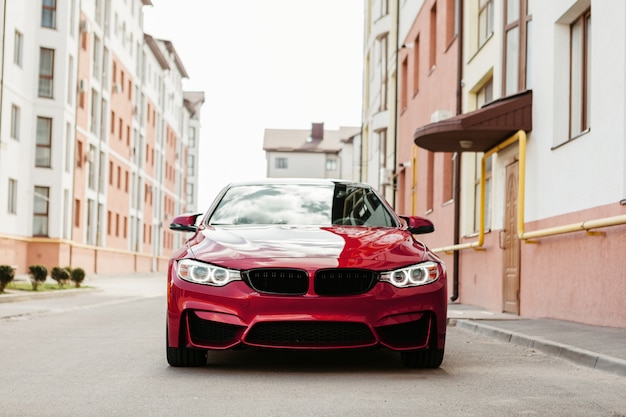 Carro vermelho moderno estacionado perto da casa de luxo