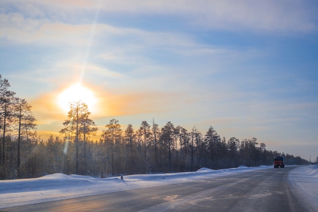 Carros circulam em uma estrada de inverno em um dia ensolarado