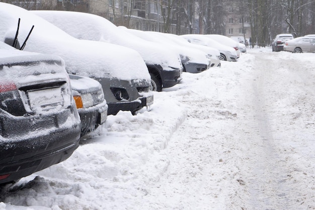 Foto carros cobertos de neve branca fresca. conceito de queda de neve no inverno e problemas com a remoção de montes de neve