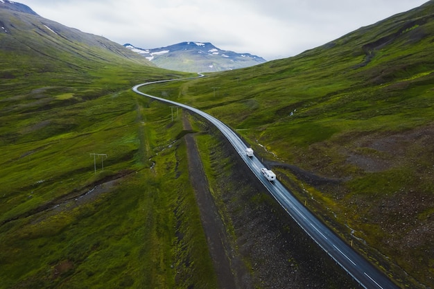 Carros dirigindo em uma bela paisagem remota de fundo de viagens rodoviárias aéreas da Islândia