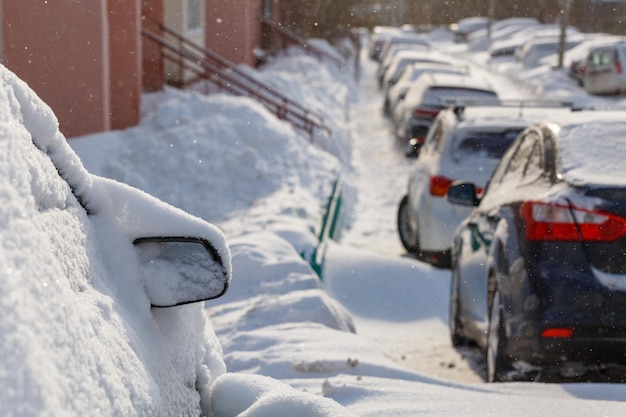 Foto carros enterrados sob a neve no estacionamento perto do edifício residencial à luz do dia ensolarado