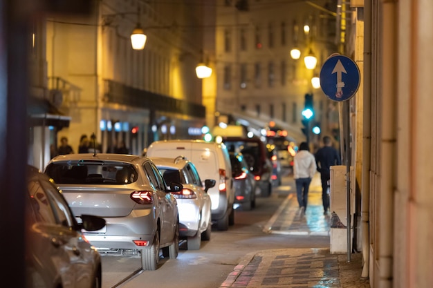 Carros ficam em um engarrafamento em uma rua estreita de lisboa à noite