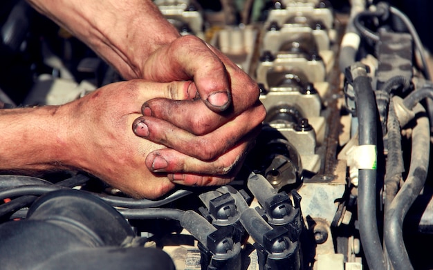 Carros de mano sucios de un mecánico de automóviles que aprietan las tuercas mientras reparan un automóvil