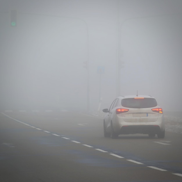 Carros no nevoeiro Mau tempo de inverno e tráfego automóvel perigoso na estrada Veículos leves no nevoeiro