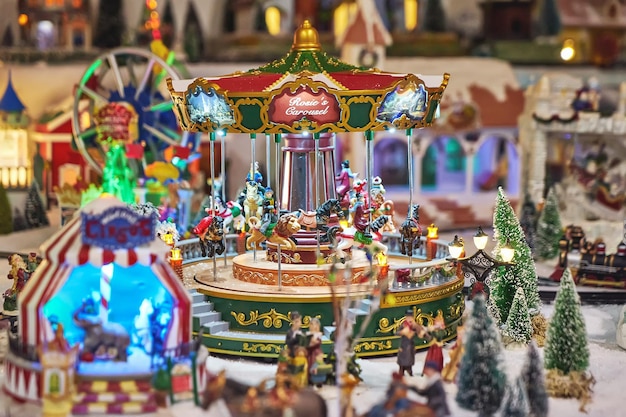 Carrossel em miniatura alegre com pessoas de brinquedo no parque de inverno durante o mercado de Natal